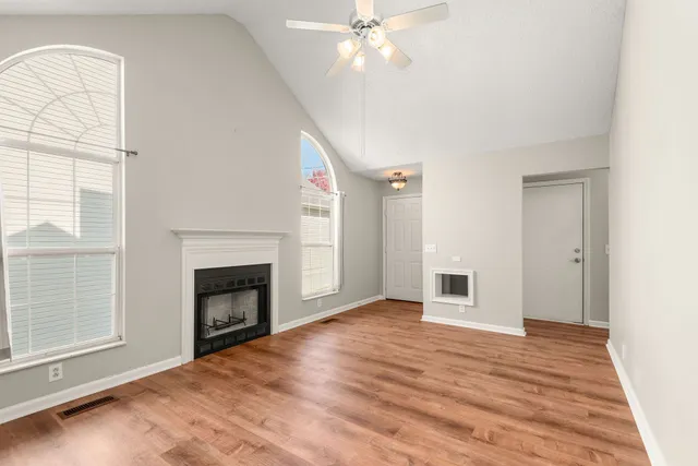 an empty room with windows fireplace and fans