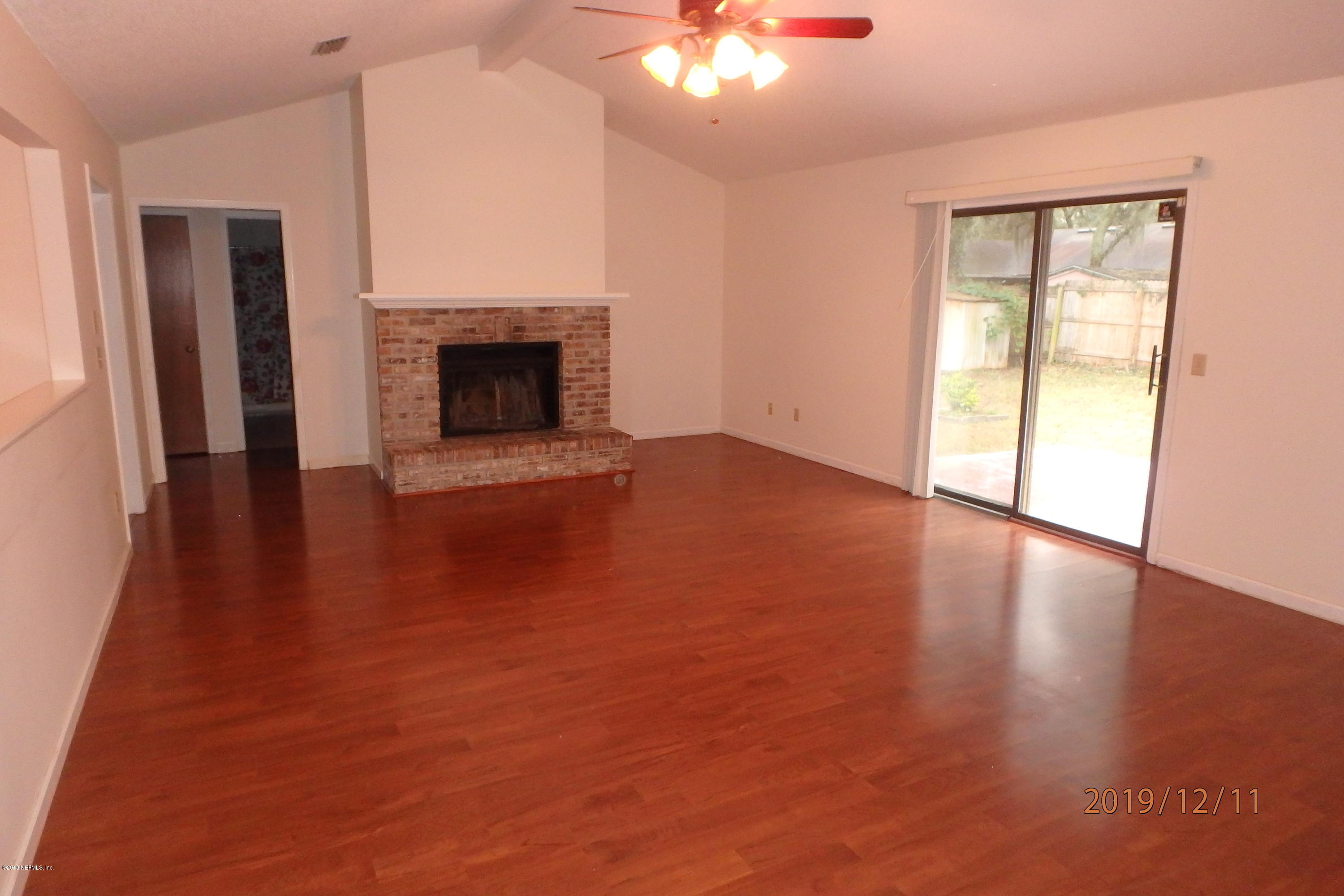 2064 Derringer Road Jacksonville, FL 32225 - Photo 4 of 17 an empty room with wooden floor a fireplace and windows