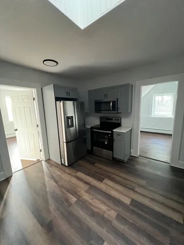 a living room with stainless steel appliances kitchen island granite countertop a refrigerator and a stove top oven