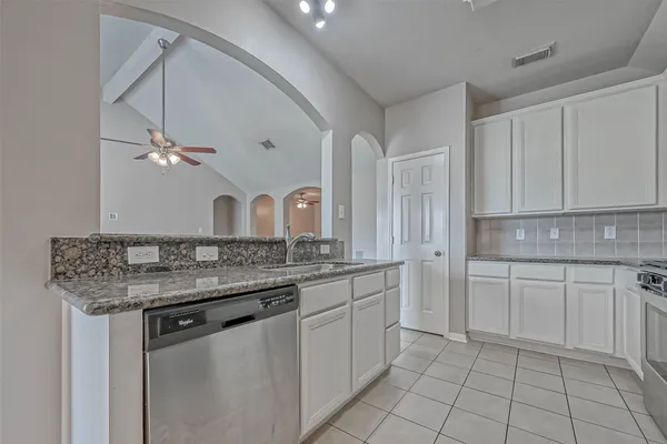 a kitchen with a sink dishwasher a stove and white cabinets