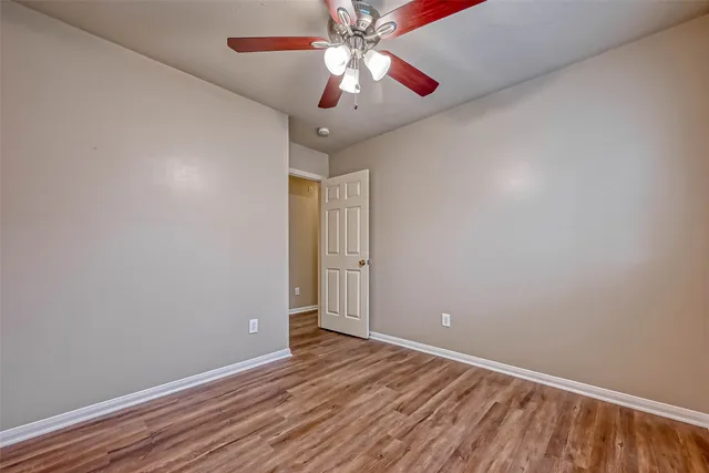 a view of an empty room with window and wooden floor