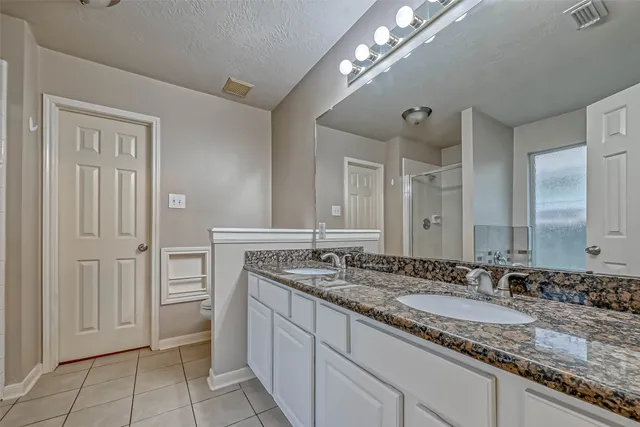 a bathroom with a granite countertop double vanity sink and a mirror