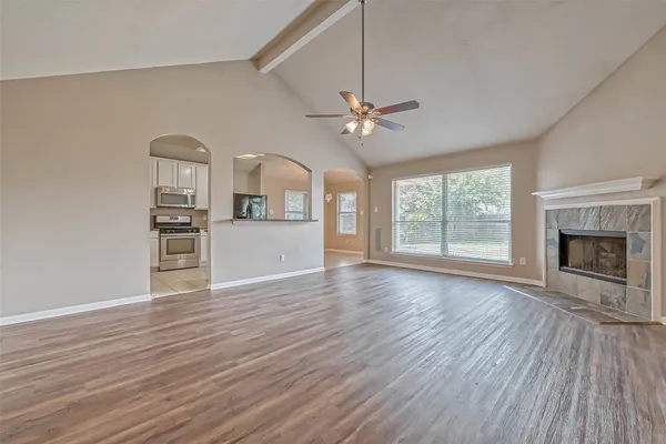 an empty room with wooden floor fireplace and windows