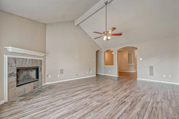 a view of an empty room with a fireplace and a chandelier fan