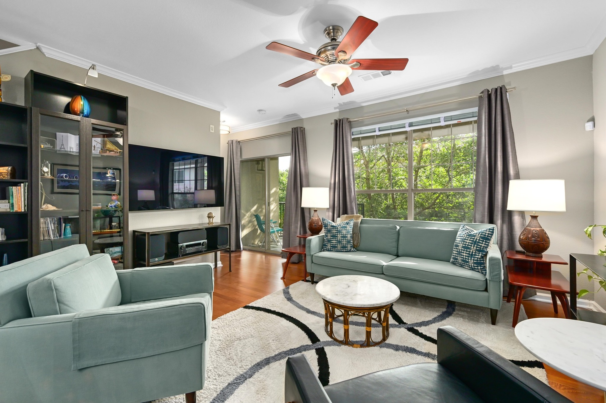 11203 Ranch Road 2222, Unit 1104 Austin, TX 78730 - Photo 7 of 23 Living room with, crown molding, wood floors, and sliding glass door to outside balcony overlooking greenspace