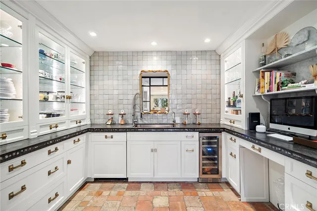 a large kitchen with granite countertop a sink white cabinets and stainless steel appliances