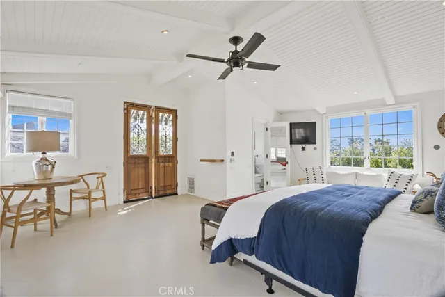 a spacious bedroom with a bed a table and large windows