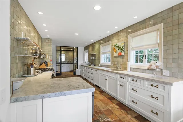 a large kitchen with granite countertop a large counter top cabinets and stainless steel appliances