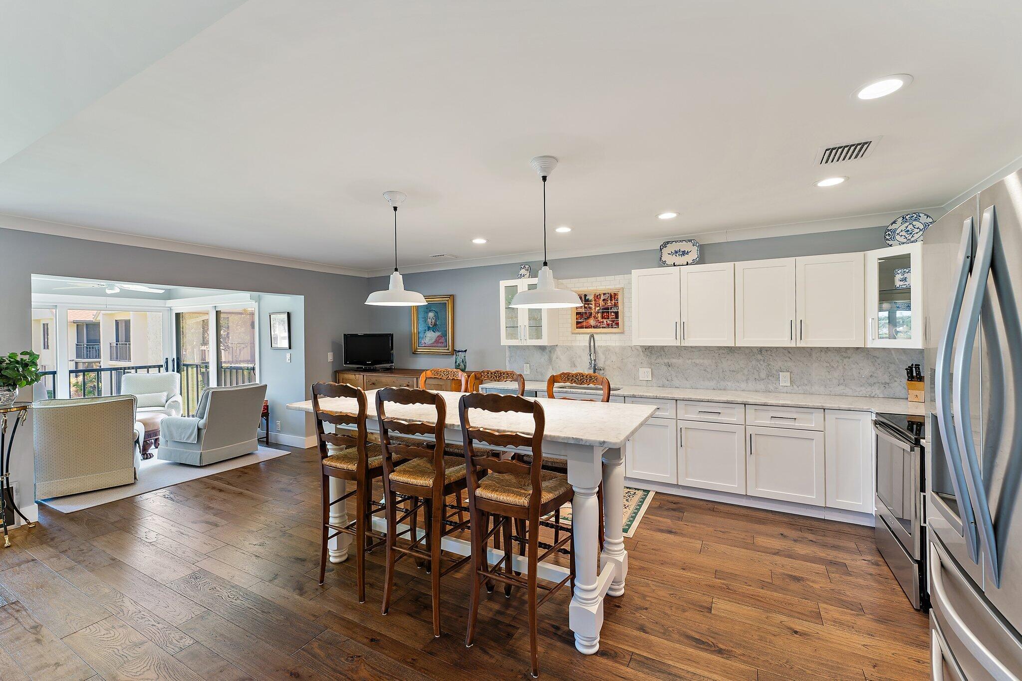 19101 Southeast Sea Turtle Court, Unit 202 Jupiter, FL 33469 - Photo 13 of 35 a kitchen with a dining table chairs wooden floor and appliances