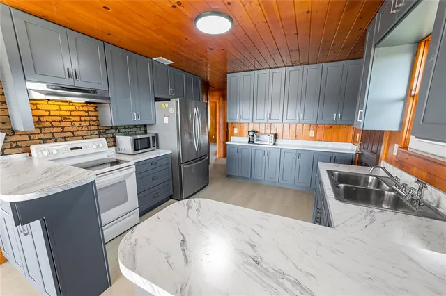 a kitchen with granite countertop a sink stove refrigerator and cabinets