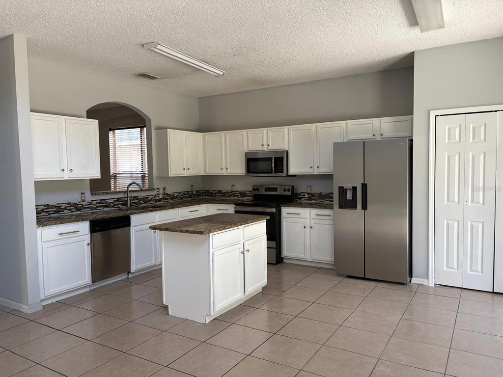 3078 Barbados Lane Haines City, FL 33844 - Photo 6 of 14 a kitchen with stainless steel appliances granite countertop a stove a sink and a refrigerator