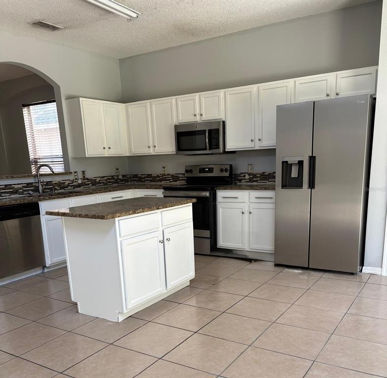 3078 Barbados Lane Haines City, FL 33844 - Photo 7 of 14 a kitchen with stainless steel appliances granite countertop a stove a sink and a refrigerator