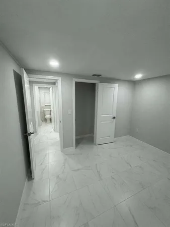 an empty room with white cabinet and mirrors