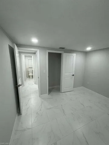 an empty room with white cabinet and mirrors