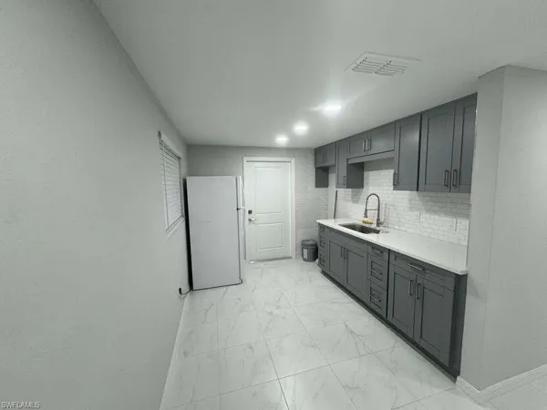 a large white kitchen with a sink and dishwasher a refrigerator with white cabinets