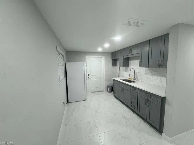 a large white kitchen with a sink and dishwasher a refrigerator with white cabinets
