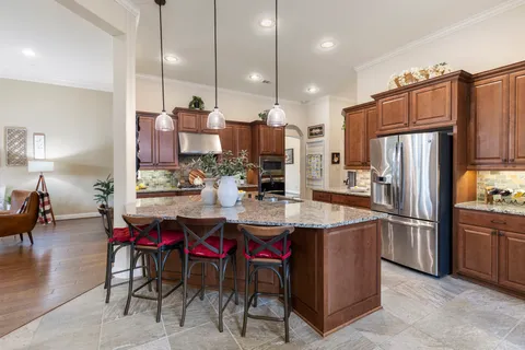 a kitchen with stainless steel appliances kitchen island granite countertop a table chairs and a refrigerator