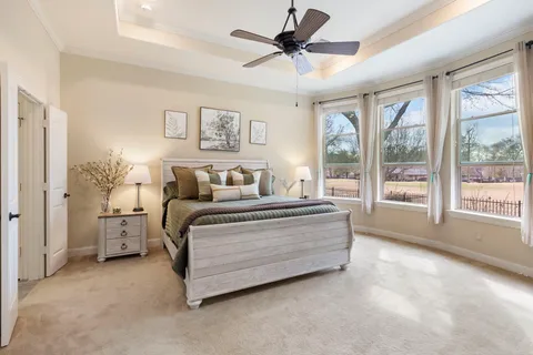 a spacious bedroom with a large bed and a chandelier fan
