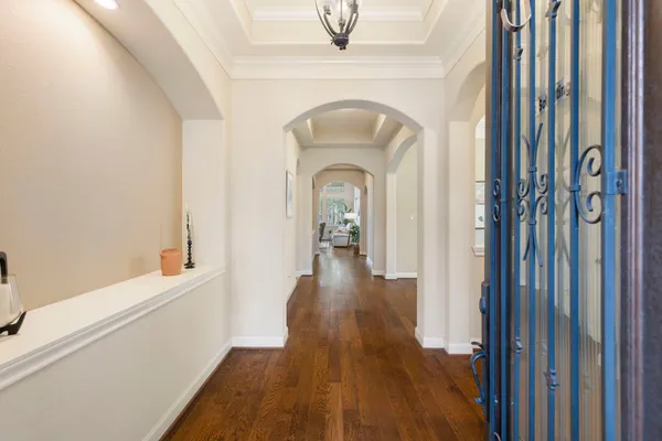 a view of a hallway with wooden floor and a bathroom