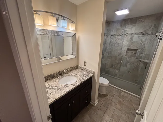 a bathroom with a granite countertop sink a toilet and shower