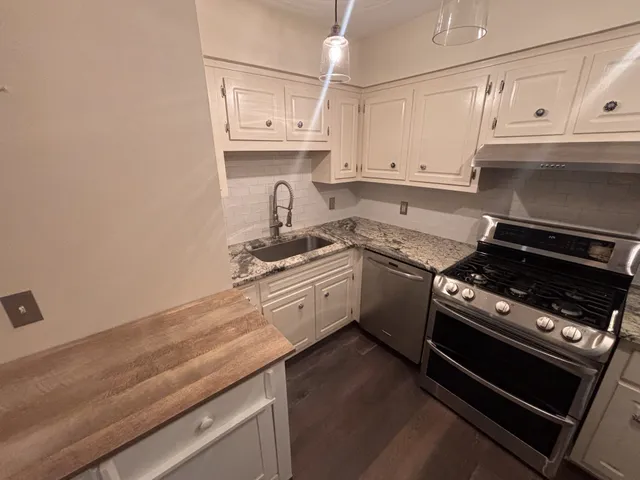 a kitchen with granite countertop a stove sink and cabinets