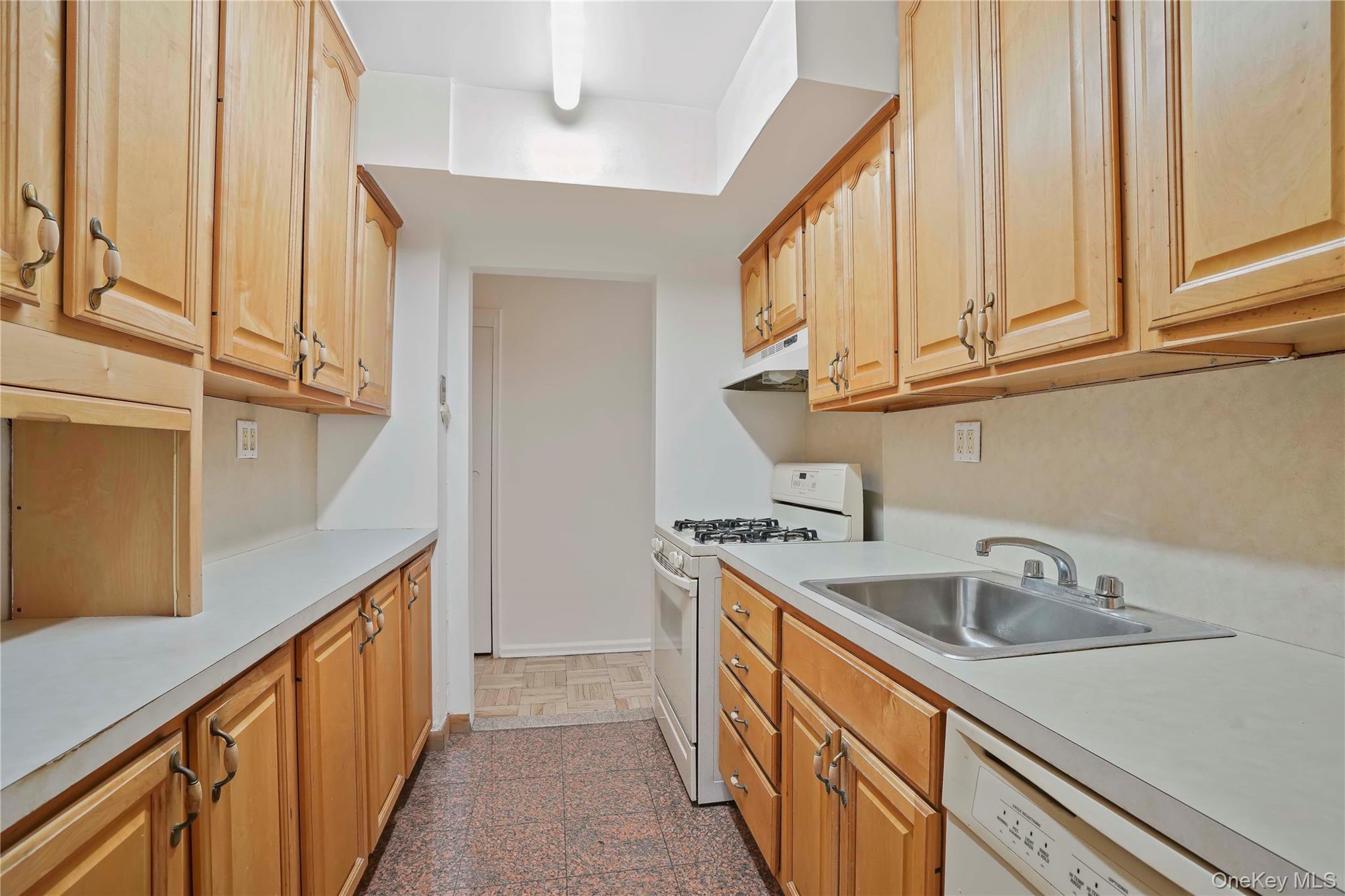 151-31 88th Street, Unit 1B Queens, NY 11414 - Photo 10 of 24 a kitchen with stainless steel appliances granite countertop a sink and dishwasher a refrigerator with wooden cabinets