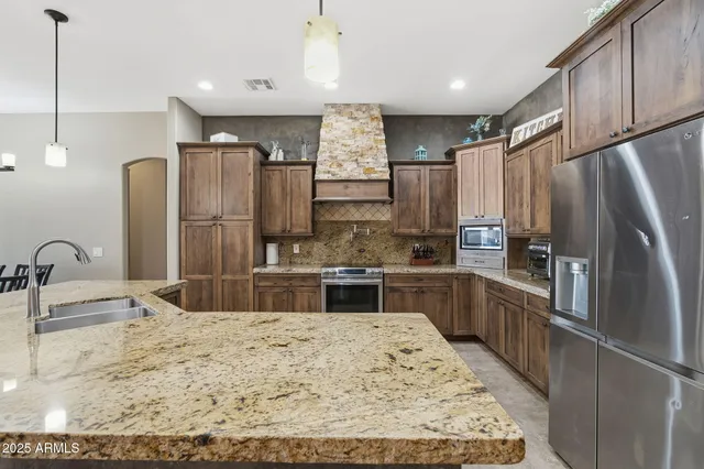 a kitchen with stainless steel appliances granite countertop a sink refrigerator and cabinets