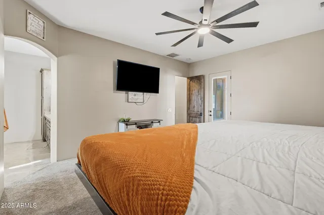 a bedroom with a bed a flat screen tv and a chandelier