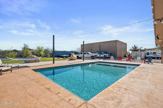 a view of a swimming pool with a patio and a yard