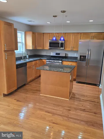 a kitchen with stainless steel appliances granite countertop a refrigerator a stove a sink and a microwave