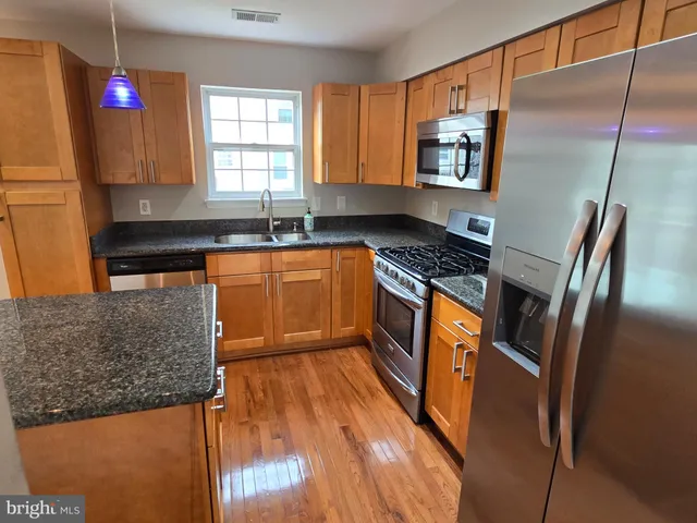 a kitchen with stainless steel appliances granite countertop a sink a stove and a refrigerator