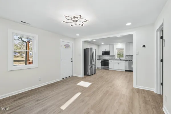 a view of a kitchen with a fridge wooden floor and a window