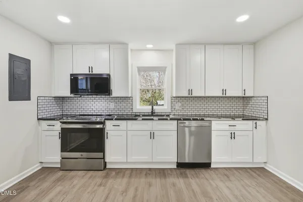 a kitchen with stainless steel appliances granite countertop a stove and white cabinets