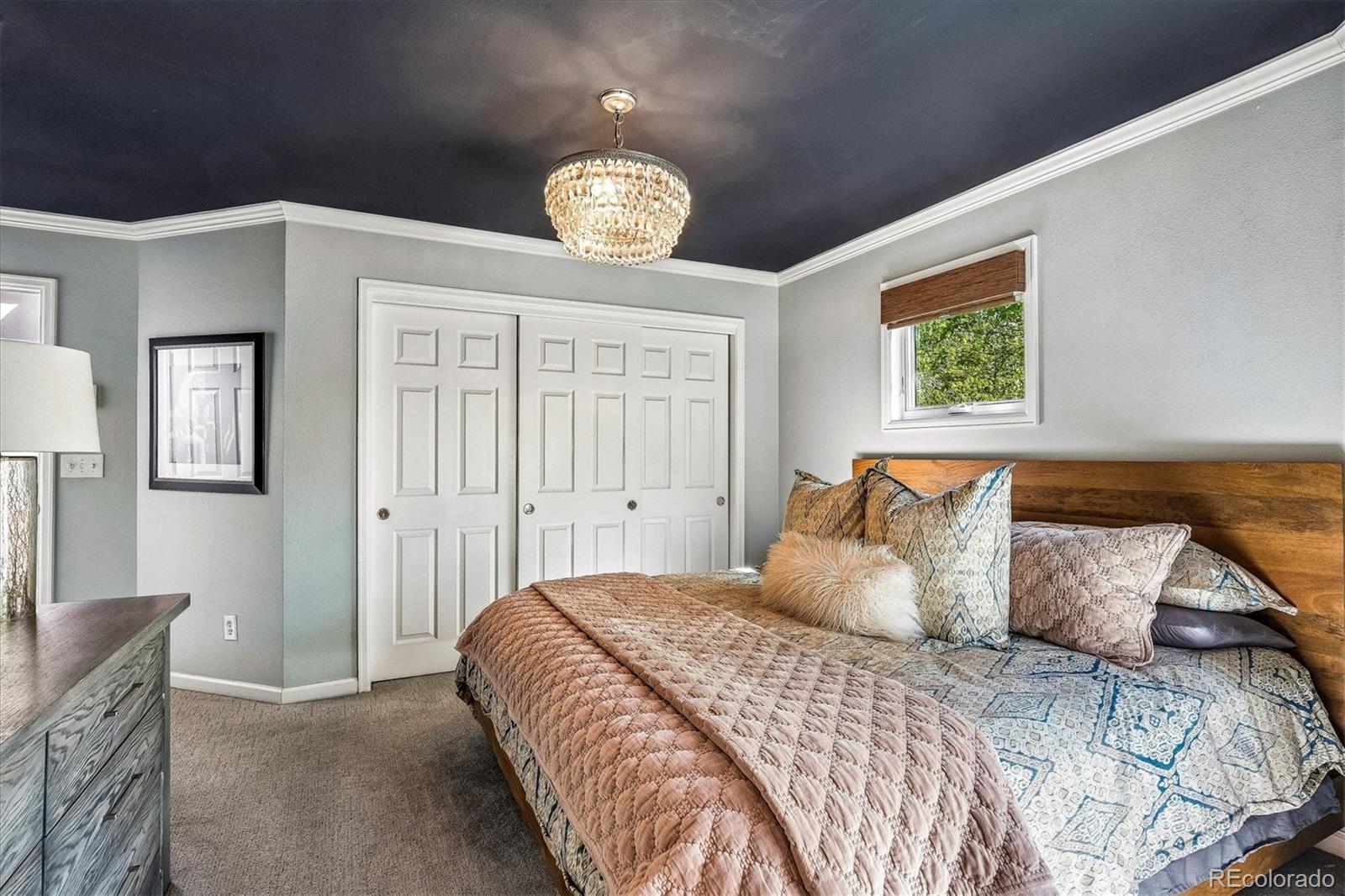 155 South Jackson Street, Unit A Denver, CO 80209 - Photo 15 of 40 a bedroom with a large bed and a chandelier