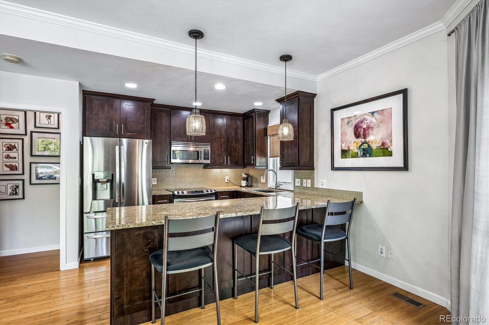 155 South Jackson Street, Unit A Denver, CO 80209 - Photo 8 of 40 a kitchen with stainless steel appliances kitchen island granite countertop a dining table chairs refrigerator and microwave