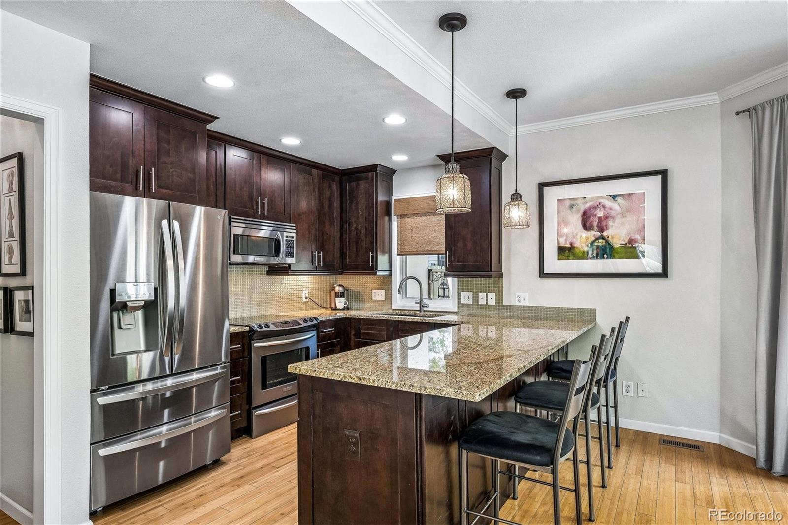 155 South Jackson Street, Unit A Denver, CO 80209 - Photo 9 of 40 a kitchen with granite countertop a table chairs refrigerator and microwave