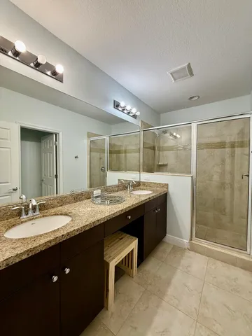 a spacious bathroom with a granite countertop sink a toilet a mirror and shower