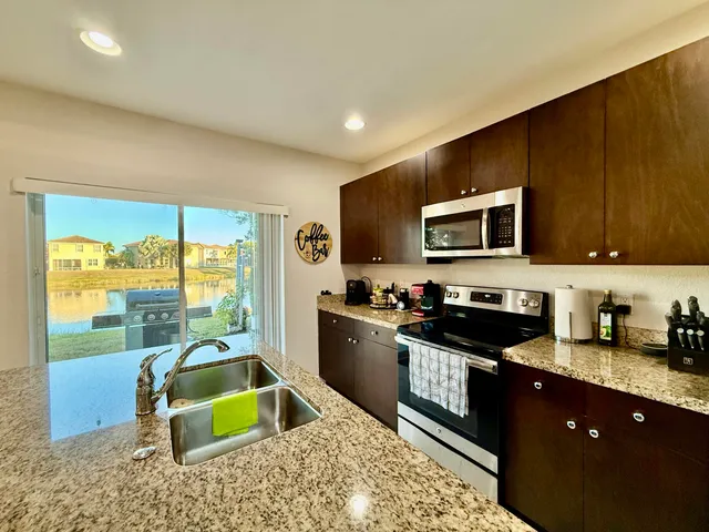 a kitchen with granite countertop a stove a sink and a microwave