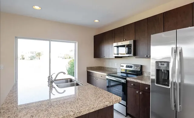 a kitchen with stainless steel appliances granite countertop a refrigerator a stove a sink and a microwave