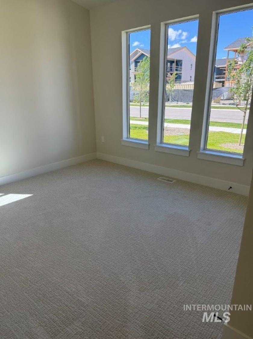 683 West Wrangler Street Meridian, ID 83646 - Photo 15 of 23 Room featuring three vertical windows, neutral-toned carpeting, light-colored walls, and white baseboards