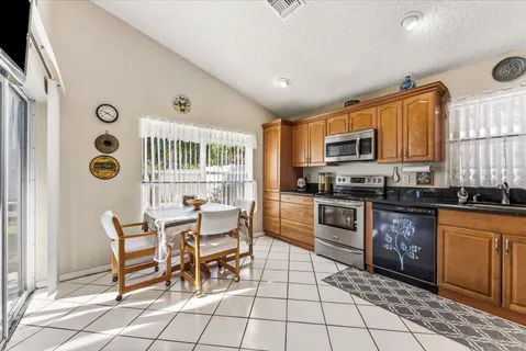 a kitchen with stainless steel appliances granite countertop a stove top oven a sink a dining table and chairs