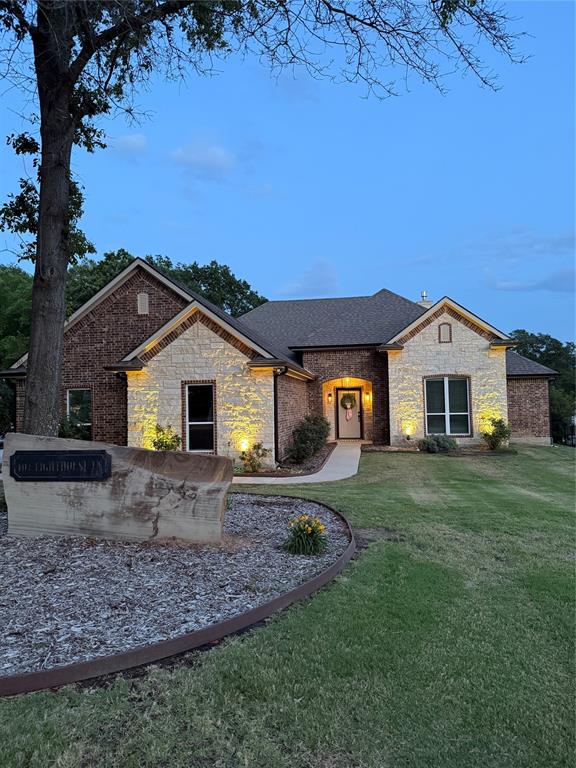 101 Lighthouse Lane Mabank, TX 75143 - Photo 30 of 40 Brick and stone facade residence featuring a covered entryway, arched details, and integrated exterior lighting