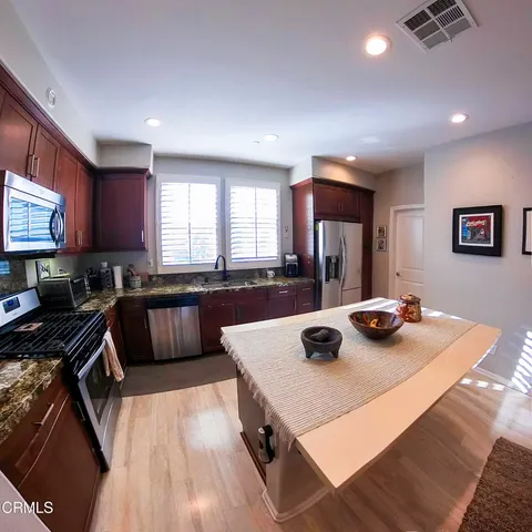 a kitchen with a refrigerator a stove a sink dishwasher and wooden cabinets with wooden floor