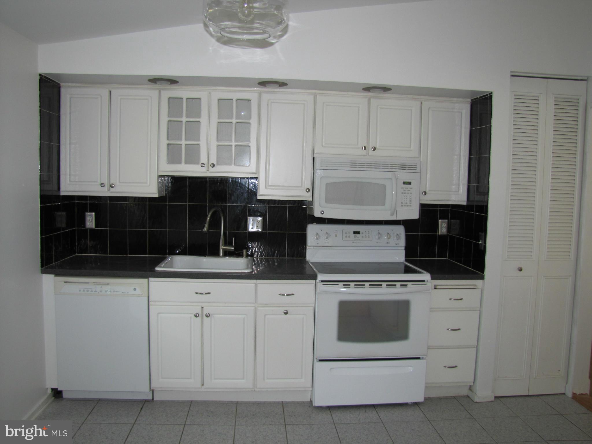 6348 Sandchain Road Columbia, MD 21045 - Photo 6 of 24 a kitchen with white cabinets and white appliances