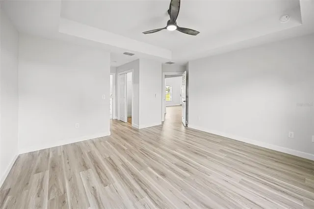 an empty room with wooden floor and ceiling fan