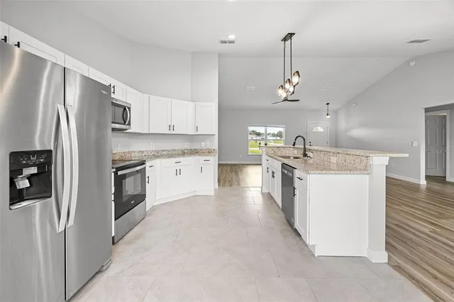 a kitchen with stainless steel appliances kitchen island granite countertop a refrigerator a stove a sink dishwasher a refrigerator with wooden floor