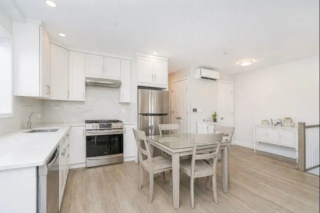 a kitchen with stainless steel appliances granite countertop a dining table chairs stove refrigerator and cabinets