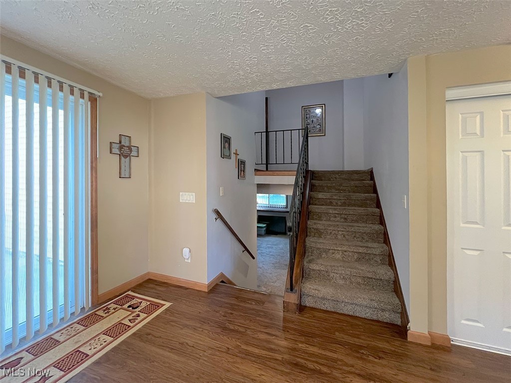 613 Guilford Road Vermilion, OH 44089 - Photo 8 of 26 Staircase with plenty of natural light, wood finished floors, and a textured ceiling