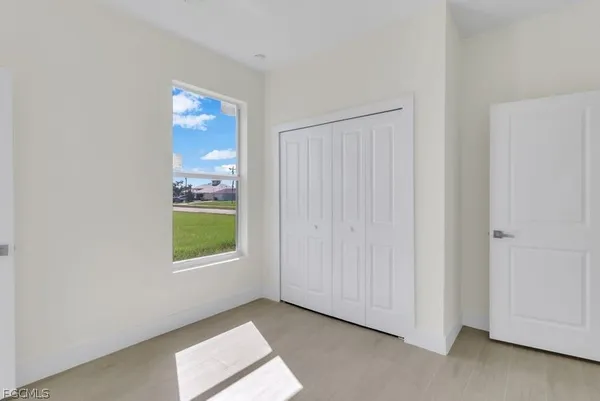 a view of an empty room with a window and a kitchen