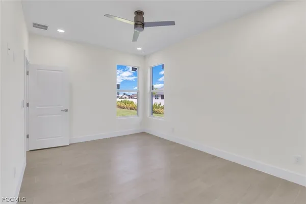 an empty room with windows and fan